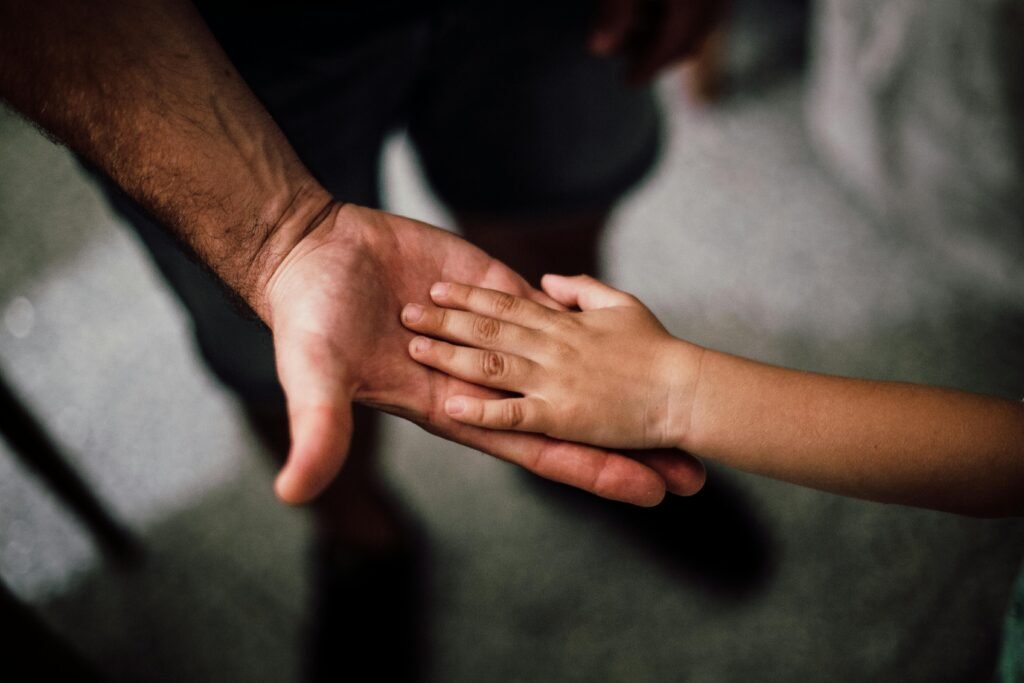 October 17th is Developmental Language Disorder (DLD) Awareness Day! Close-up of a child's hand resting gently on a man's hand, symbolizing love and support.